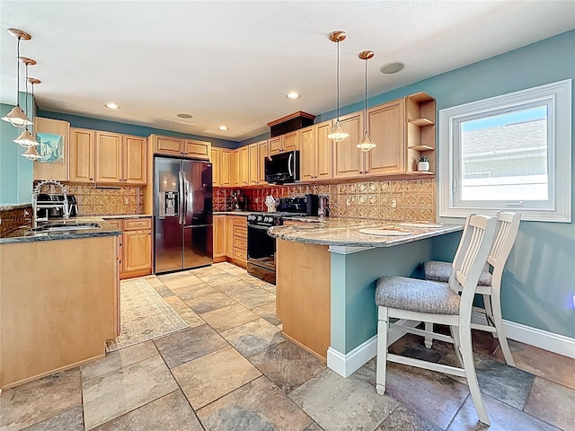 kitchen featuring a peninsula, black appliances, and stone tile flooring