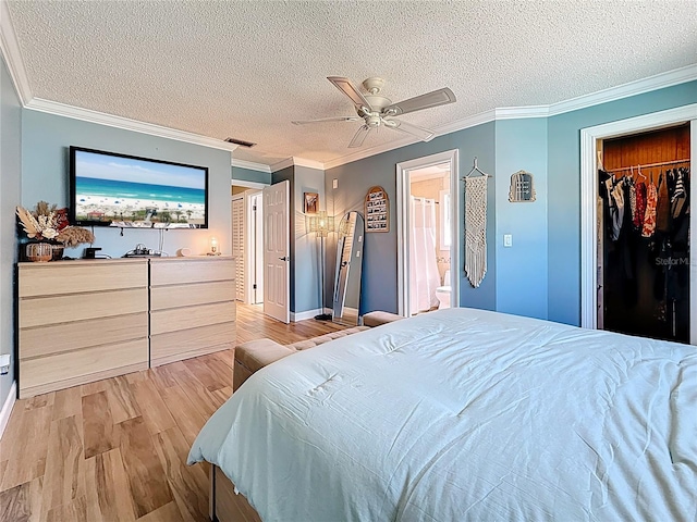 bedroom featuring wood finished floors, visible vents, ornamental molding, a textured ceiling, and a walk in closet