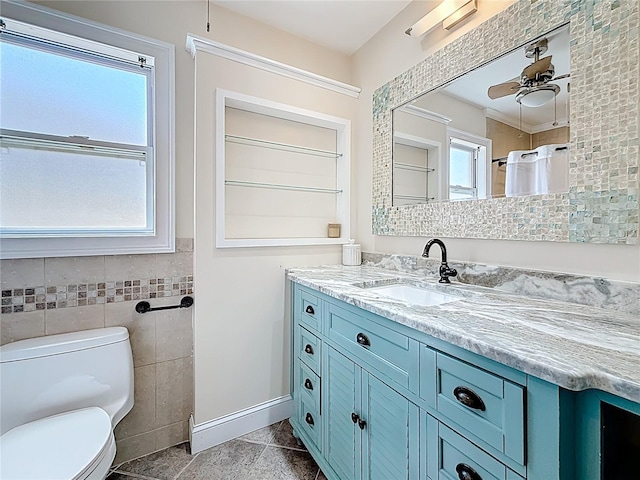 full bathroom featuring a wealth of natural light, toilet, tile walls, and vanity