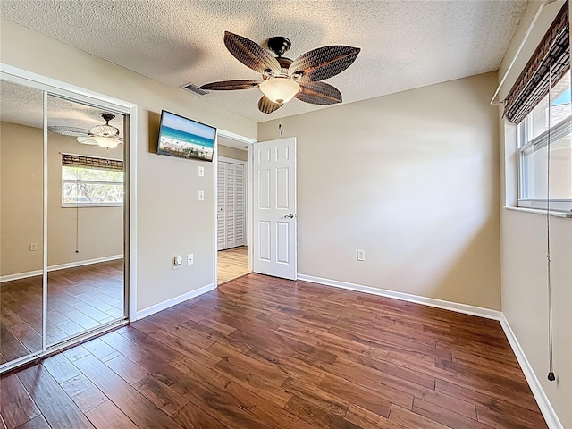 unfurnished bedroom with a ceiling fan, a textured ceiling, wood finished floors, a closet, and baseboards