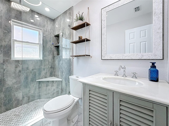 full bath with visible vents, tiled shower, toilet, and vanity