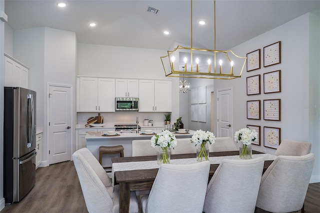 dining room featuring visible vents, recessed lighting, a towering ceiling, a notable chandelier, and dark wood-style flooring