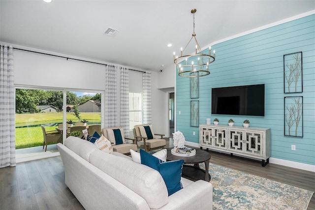 living room with wood finished floors, visible vents, baseboards, lofted ceiling, and a notable chandelier