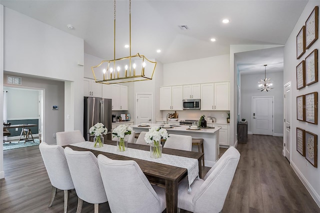 dining space with dark wood finished floors, a notable chandelier, and high vaulted ceiling