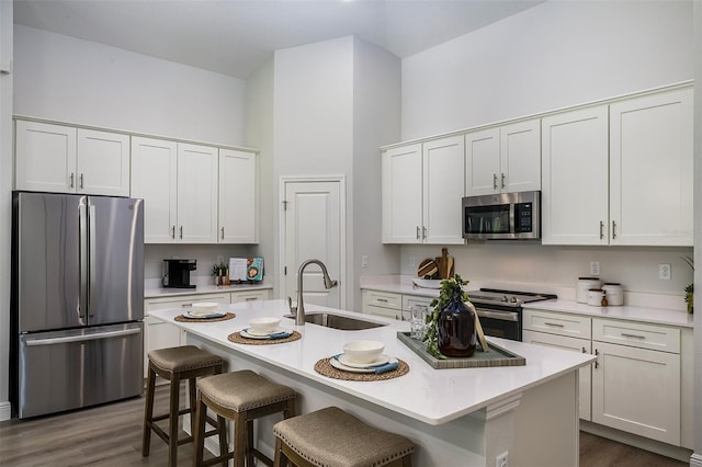 kitchen with a kitchen bar, light countertops, appliances with stainless steel finishes, and a sink