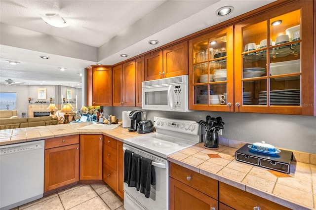 kitchen with white appliances, brown cabinetry, and a sink