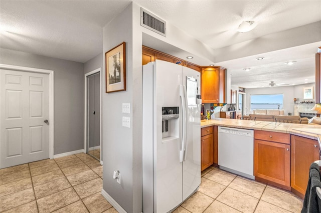 kitchen featuring white appliances, visible vents, ceiling fan, light countertops, and brown cabinets