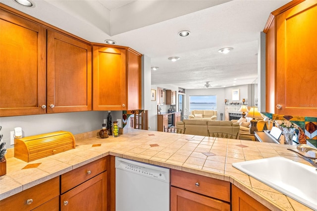 kitchen featuring ceiling fan, open floor plan, light countertops, white dishwasher, and a sink