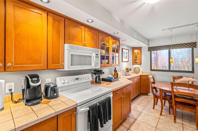 kitchen featuring white appliances, tile counters, and brown cabinetry