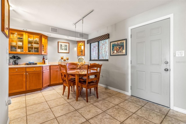 dining room featuring track lighting, light tile patterned floors, baseboards, and visible vents