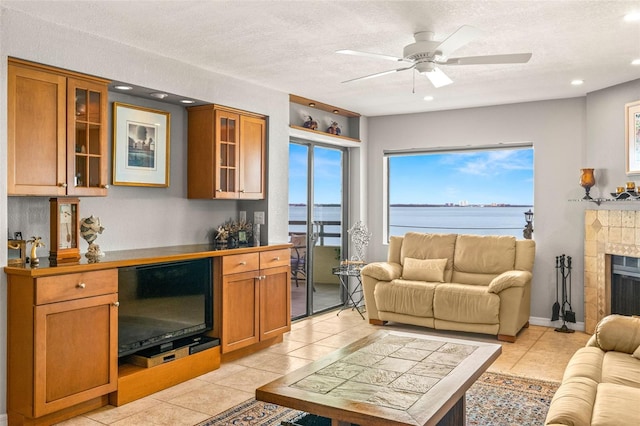 living room with a tiled fireplace, a textured ceiling, recessed lighting, light tile patterned floors, and ceiling fan