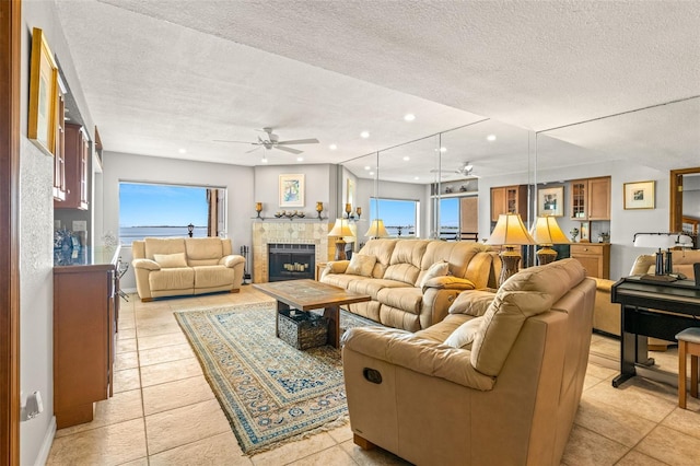 living area featuring recessed lighting, a textured ceiling, ceiling fan, and a tiled fireplace