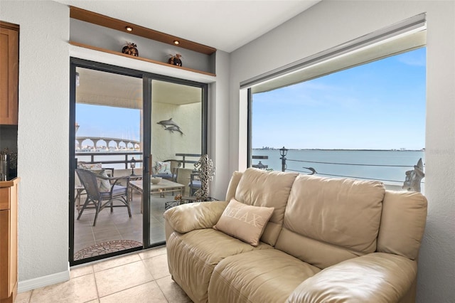 living area with a water view, plenty of natural light, and light tile patterned flooring