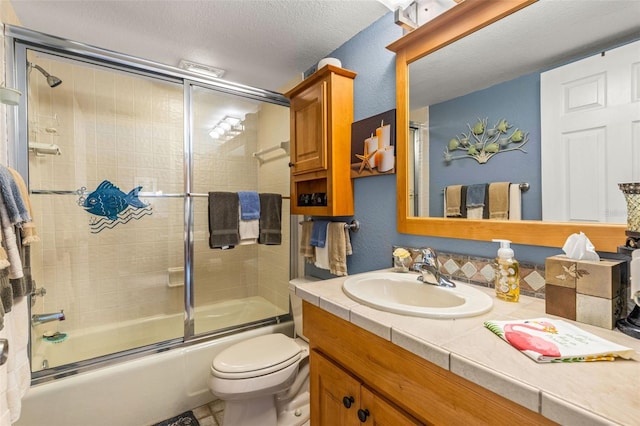 full bath with vanity, toilet, shower / bath combination with glass door, and a textured ceiling