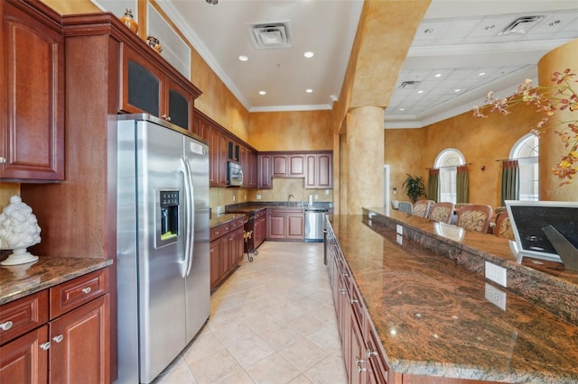 kitchen with visible vents, stainless steel appliances, dark stone counters, crown molding, and glass insert cabinets