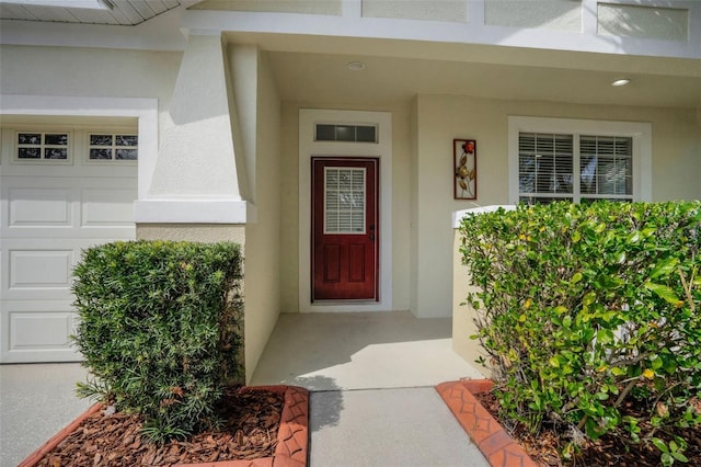 property entrance with stucco siding and a garage