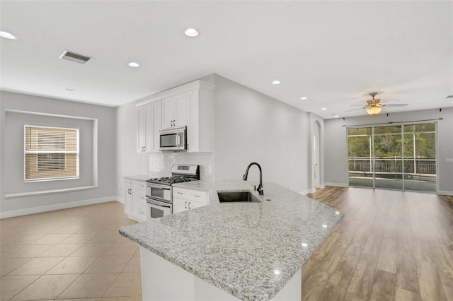 kitchen with visible vents, a sink, open floor plan, stainless steel appliances, and decorative backsplash