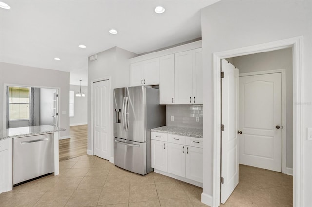 kitchen featuring light stone counters, decorative backsplash, white cabinets, and appliances with stainless steel finishes