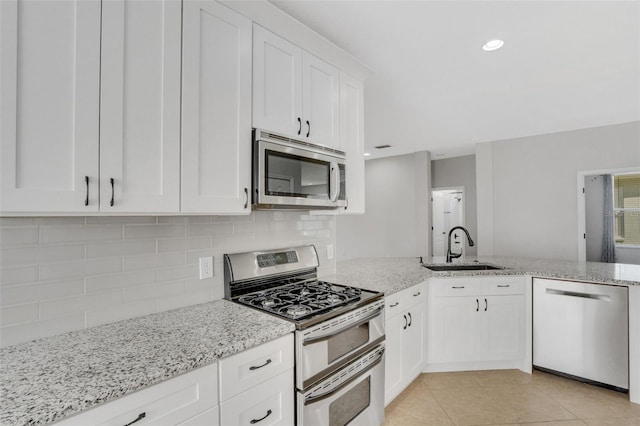 kitchen with light tile patterned floors, decorative backsplash, white cabinets, stainless steel appliances, and a sink