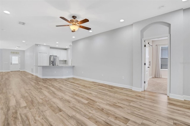 unfurnished living room featuring arched walkways, recessed lighting, light wood-type flooring, and a ceiling fan