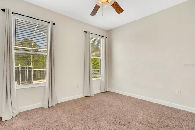 carpeted spare room featuring baseboards and a ceiling fan