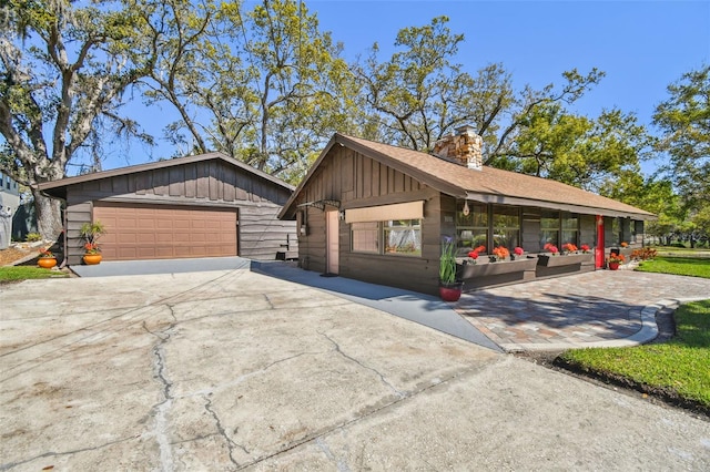 view of front of property featuring an outbuilding, board and batten siding, a chimney, and a detached garage