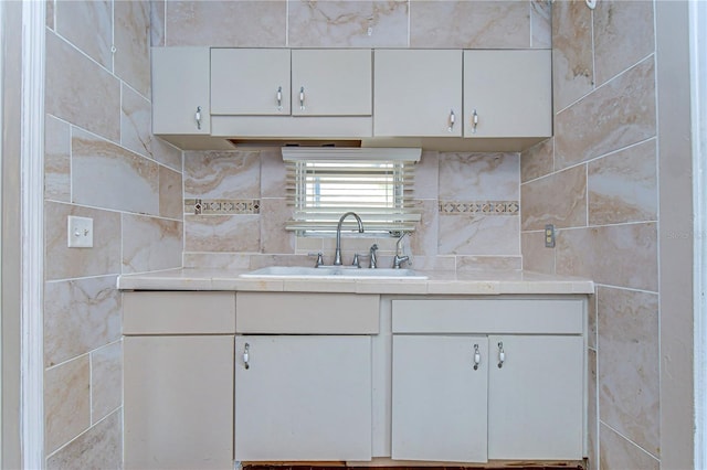 kitchen featuring white cabinetry, light countertops, and a sink