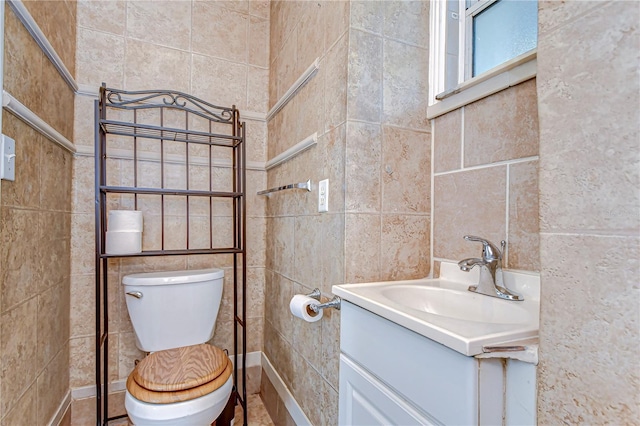 bathroom with toilet, tile walls, and vanity