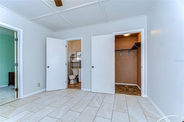 unfurnished bedroom with a walk in closet, baseboards, light tile patterned floors, ensuite bathroom, and a closet