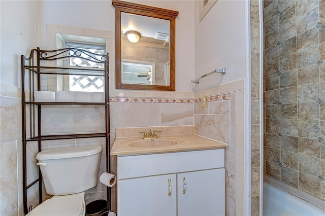 full bathroom with tiled shower, toilet, tile walls, and vanity