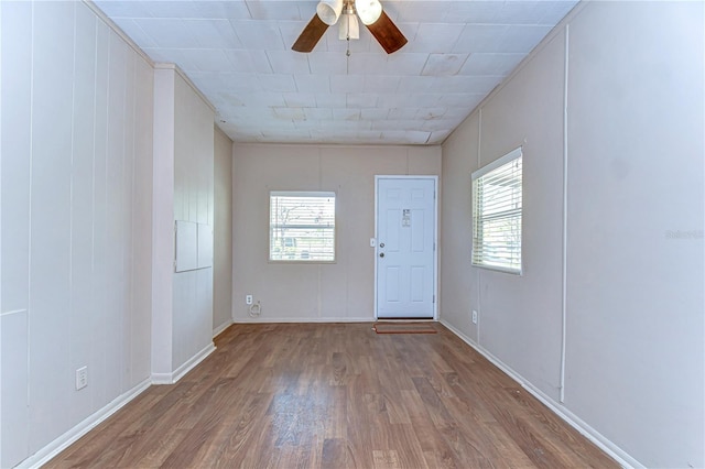 interior space featuring ceiling fan, baseboards, plenty of natural light, and wood finished floors