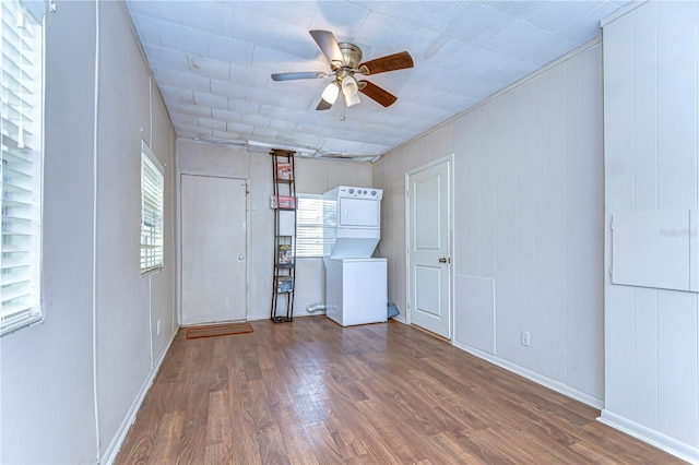 spare room featuring wood finished floors, stacked washer and dryer, and ceiling fan