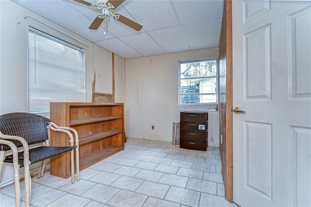 sitting room featuring a drop ceiling and ceiling fan