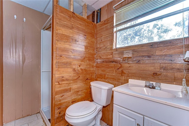 bathroom with a shower stall, toilet, vanity, and wood walls