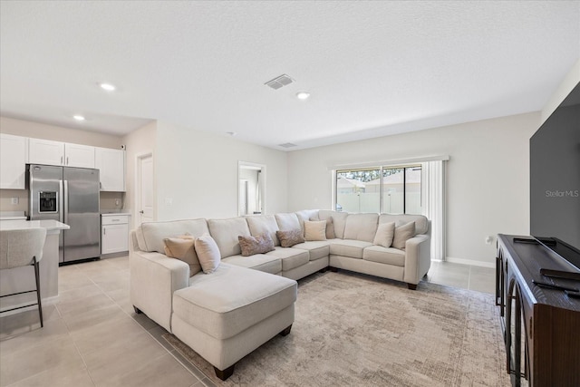 living area with light tile patterned floors, visible vents, recessed lighting, and baseboards