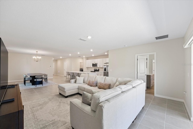 living area with light tile patterned floors, visible vents, baseboards, and an inviting chandelier