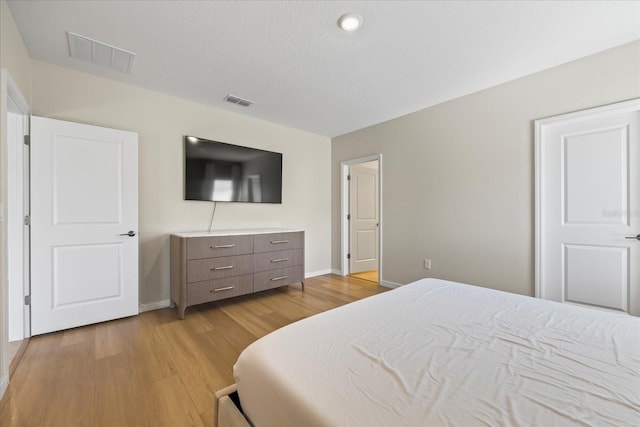 bedroom featuring visible vents, baseboards, and light wood finished floors