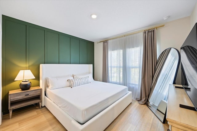 bedroom featuring light wood-style floors and a decorative wall