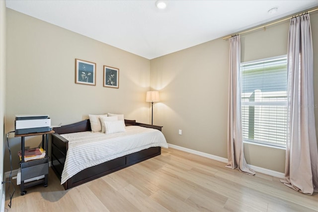 bedroom featuring light wood-type flooring, multiple windows, and baseboards