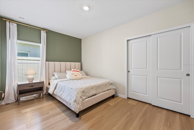 bedroom featuring a closet, light wood-style flooring, and baseboards