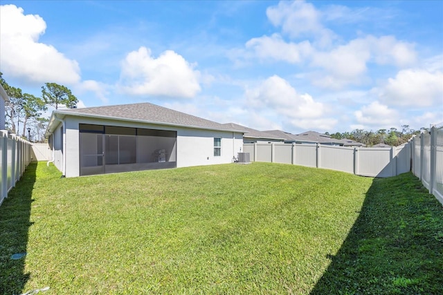 rear view of property featuring a sunroom, central AC unit, stucco siding, a fenced backyard, and a yard