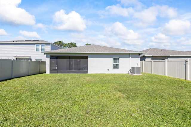 rear view of house with a lawn, a fenced backyard, a sunroom, and stucco siding