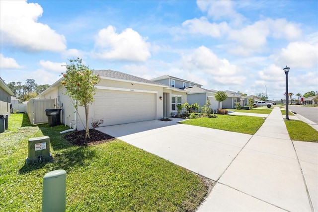 view of front of property with fence, an attached garage, stucco siding, concrete driveway, and a front lawn