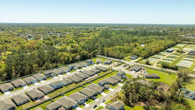 drone / aerial view featuring a wooded view and a residential view