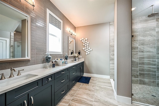 full bathroom featuring a sink, baseboards, double vanity, and a shower stall