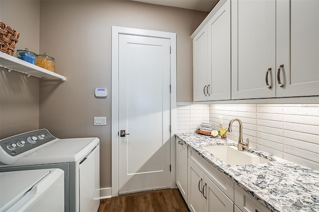 washroom with a sink, cabinet space, washing machine and dryer, and dark wood-style flooring