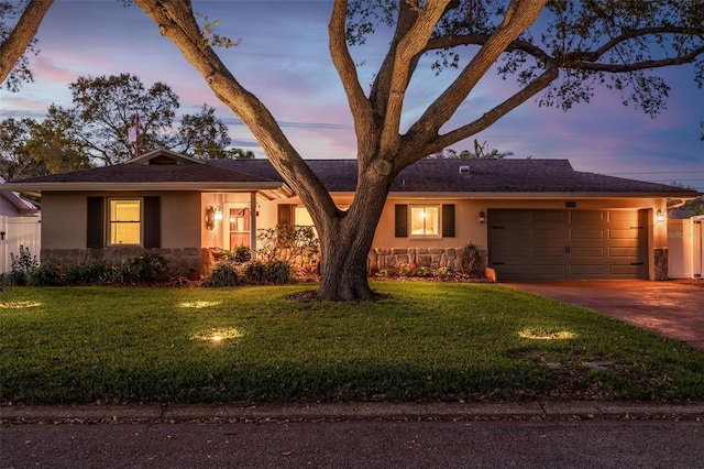 ranch-style home with stucco siding, stone siding, a garage, and driveway