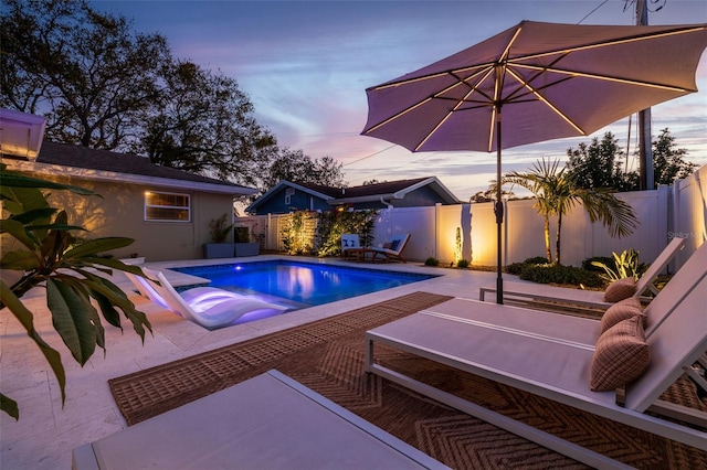 pool at dusk with a patio area, a fenced in pool, and a fenced backyard