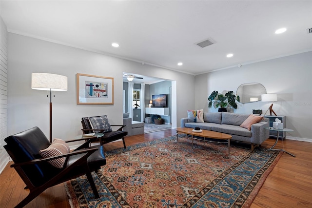 living area featuring recessed lighting, wood finished floors, baseboards, and ornamental molding