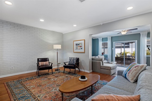 living area with recessed lighting, a ceiling fan, wood finished floors, and brick wall